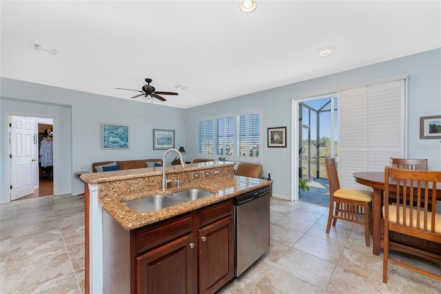 kitchen with a kitchen island with sink, sink, stainless steel dishwasher, ceiling fan, and light stone countertops