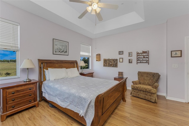 bedroom featuring a tray ceiling, ceiling fan, and light hardwood / wood-style floors