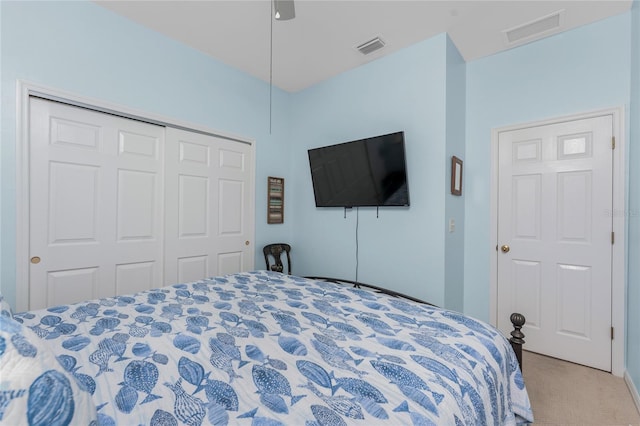 bedroom with ceiling fan, light carpet, and a closet