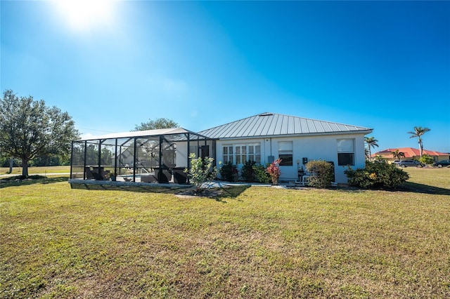 rear view of house with glass enclosure and a yard