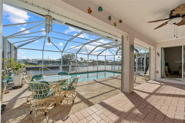 view of swimming pool with ceiling fan, a lanai, a water view, and a patio area