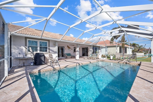 view of swimming pool featuring ceiling fan, a lanai, and a patio area