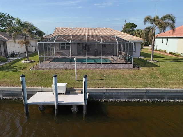 back of property with a yard, a water view, and glass enclosure