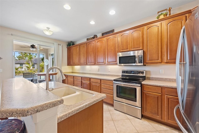 kitchen featuring ceiling fan, sink, stainless steel appliances, a center island with sink, and light tile patterned floors