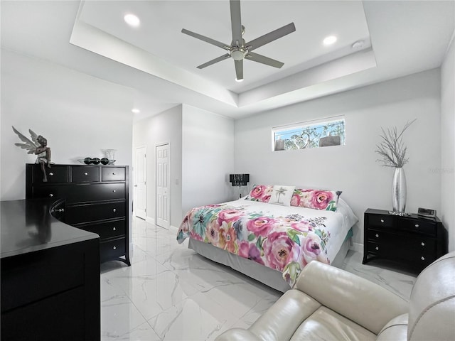 bedroom with ceiling fan, a raised ceiling, and a closet