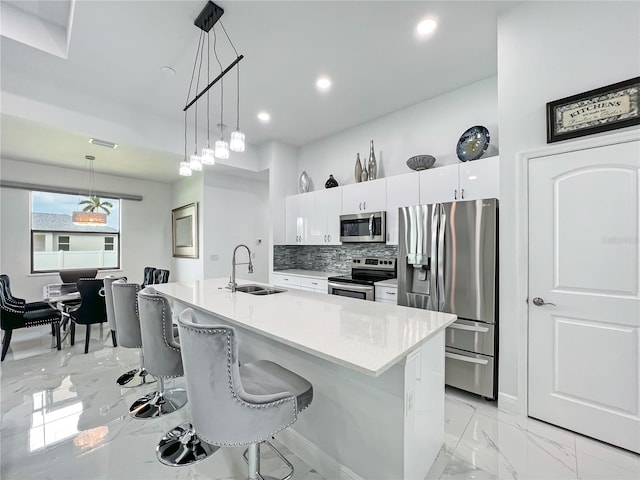 kitchen featuring hanging light fixtures, sink, appliances with stainless steel finishes, tasteful backsplash, and white cabinetry