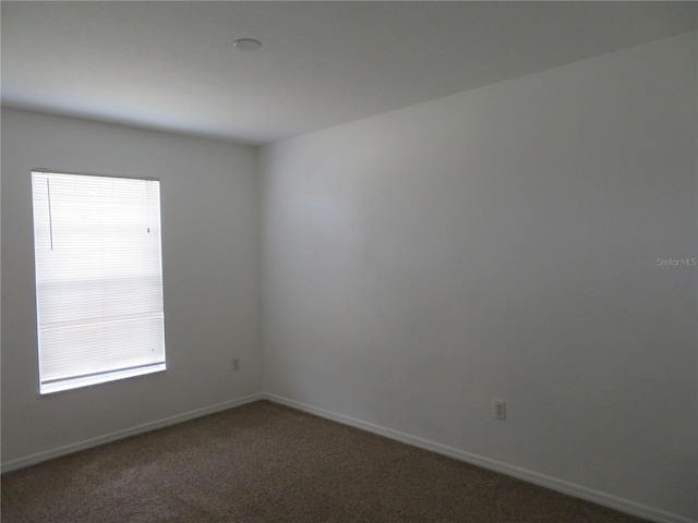 empty room featuring dark carpet and a wealth of natural light