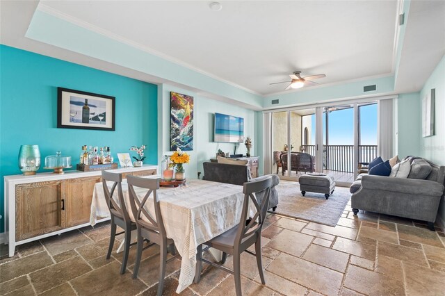 dining area with ceiling fan, a raised ceiling, and crown molding