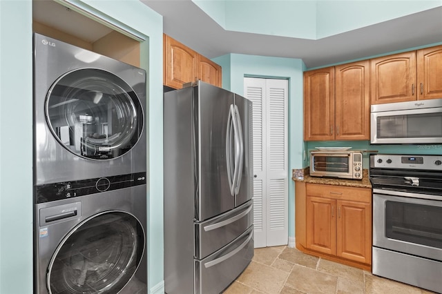 kitchen featuring stacked washing maching and dryer, stainless steel appliances, and light stone counters