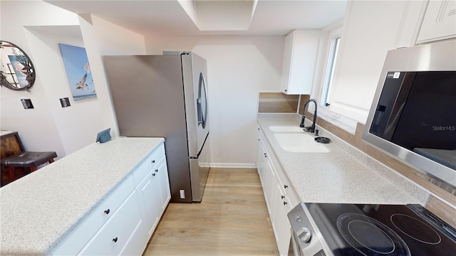 kitchen with sink, white cabinets, light wood-type flooring, and appliances with stainless steel finishes