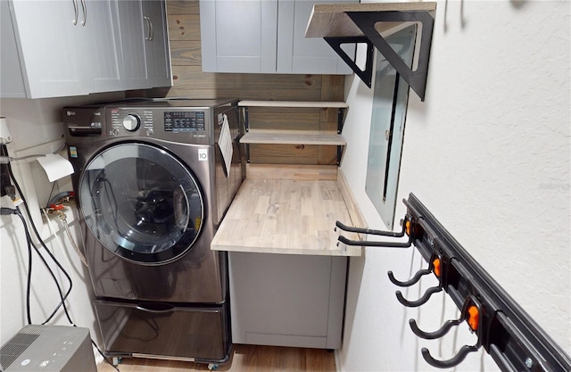 washroom with light hardwood / wood-style flooring, cabinets, and washer / dryer