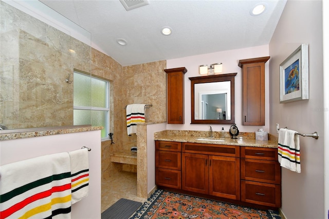 bathroom featuring tile patterned flooring, vanity, and tiled shower