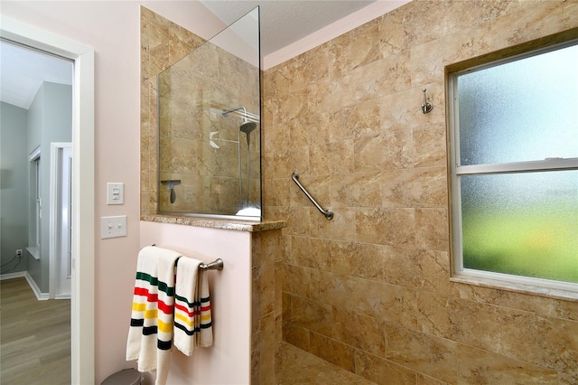 bathroom with a tile shower and hardwood / wood-style flooring