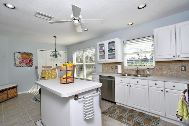 kitchen with white cabinets, sink, stainless steel dishwasher, decorative light fixtures, and a healthy amount of sunlight