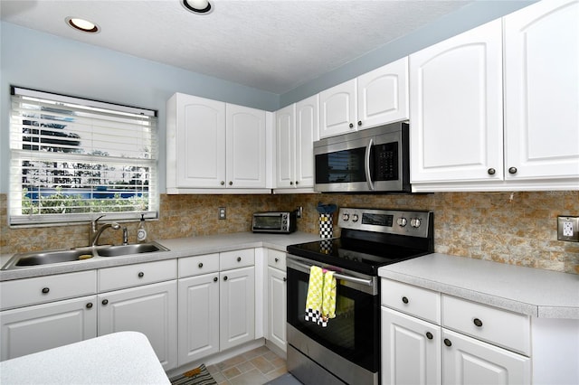 kitchen featuring appliances with stainless steel finishes, backsplash, white cabinetry, and sink