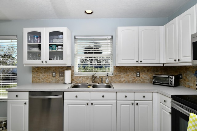 kitchen featuring tasteful backsplash, a textured ceiling, stainless steel appliances, sink, and white cabinets