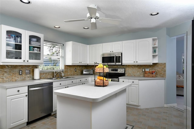 kitchen featuring appliances with stainless steel finishes, tasteful backsplash, a kitchen island, sink, and white cabinetry