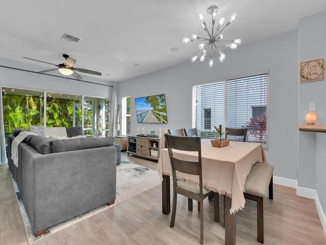 dining space with ceiling fan with notable chandelier, a healthy amount of sunlight, and light hardwood / wood-style flooring