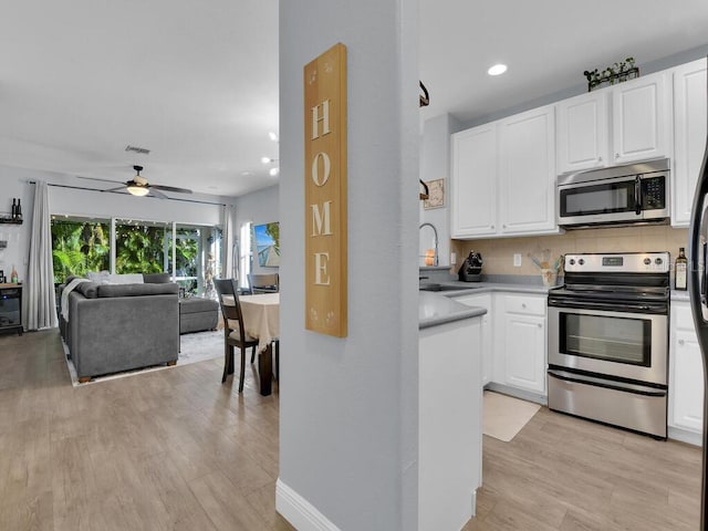 kitchen featuring ceiling fan, white cabinetry, stainless steel appliances, and tasteful backsplash