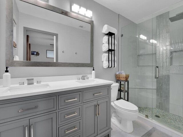 bathroom featuring tile patterned flooring, vanity, toilet, and walk in shower