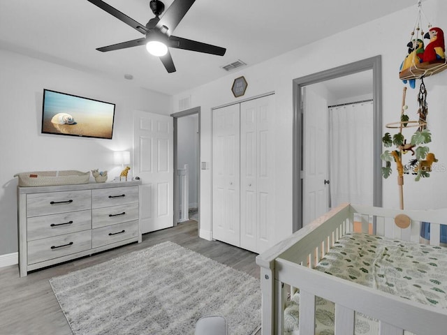 bedroom with hardwood / wood-style floors, a nursery area, a closet, and ceiling fan