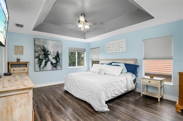 bedroom featuring dark hardwood / wood-style flooring, a raised ceiling, and ceiling fan