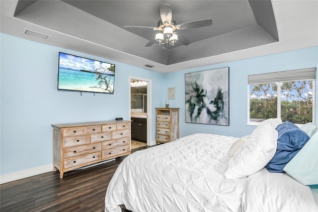 bedroom featuring ensuite bathroom, ceiling fan, a raised ceiling, and dark hardwood / wood-style flooring