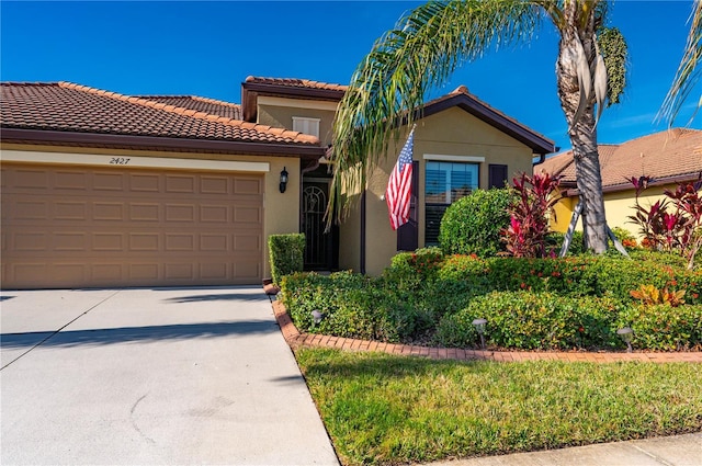 mediterranean / spanish house with concrete driveway, an attached garage, a tiled roof, and stucco siding