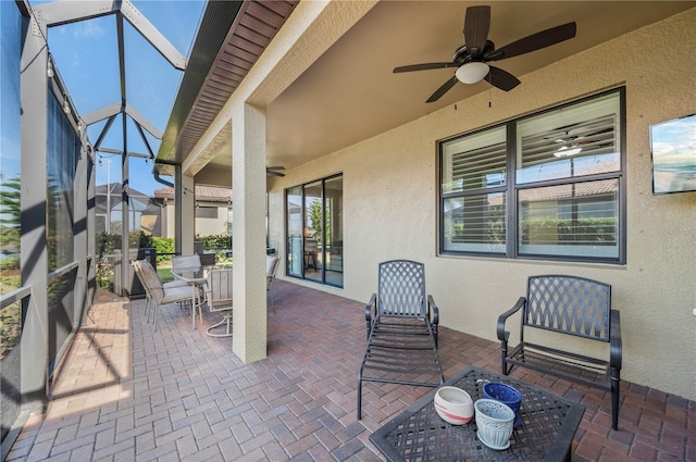 view of patio / terrace featuring glass enclosure, outdoor dining area, and a ceiling fan