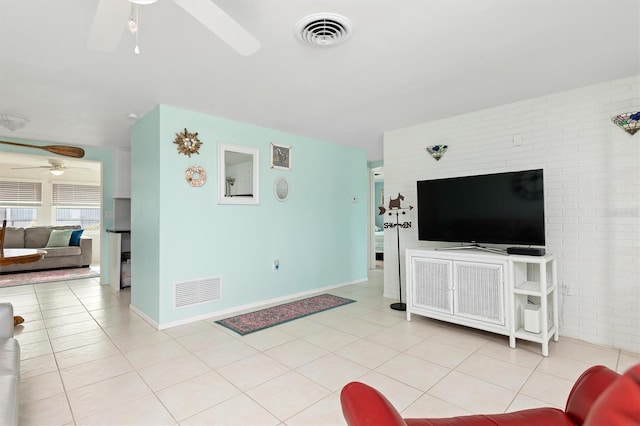 tiled living room featuring ceiling fan and brick wall