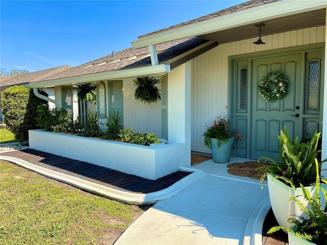 view of exterior entry with a shingled roof