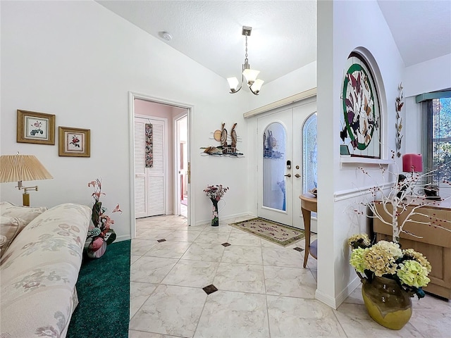 foyer entrance with french doors, vaulted ceiling, and a notable chandelier