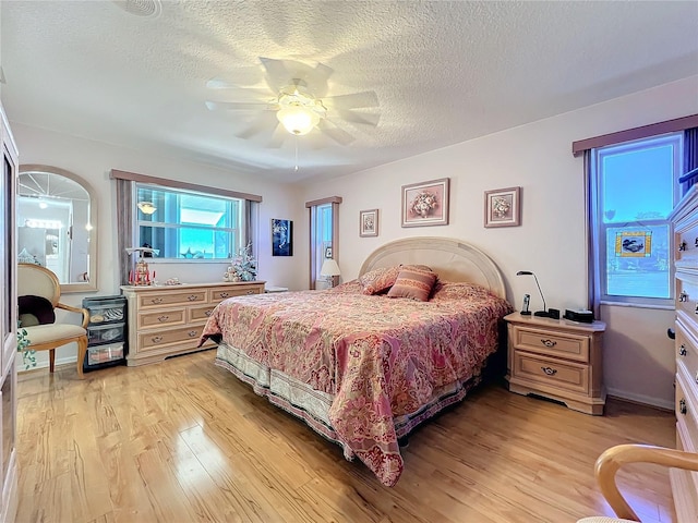 bedroom with ceiling fan, light hardwood / wood-style floors, and a textured ceiling