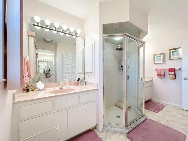 bathroom featuring tile patterned floors, vanity, a shower with shower door, and a textured ceiling