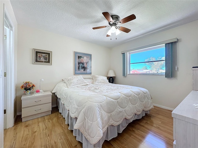 bedroom featuring ceiling fan, light hardwood / wood-style floors, and a textured ceiling