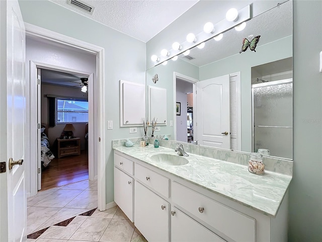 bathroom featuring tile patterned floors, an enclosed shower, vanity, a textured ceiling, and ceiling fan