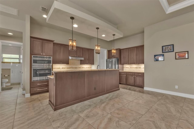 kitchen featuring decorative light fixtures, stainless steel appliances, tasteful backsplash, and an island with sink