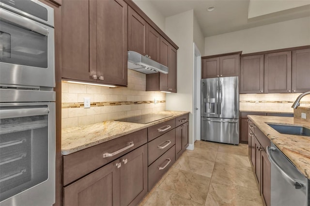 kitchen with light stone counters, sink, stainless steel appliances, and tasteful backsplash