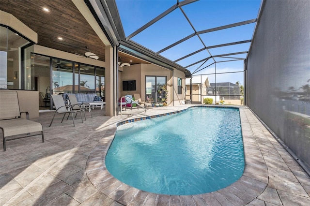 view of swimming pool with a patio area, ceiling fan, and glass enclosure