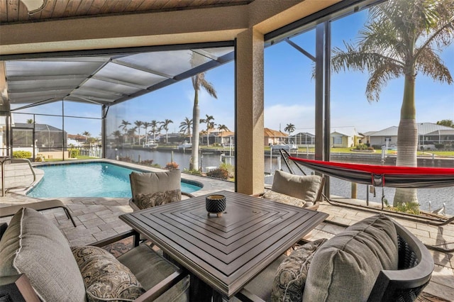 view of swimming pool with glass enclosure, a patio area, and a water view