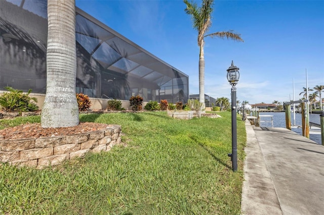 view of yard featuring a boat dock, a water view, and glass enclosure