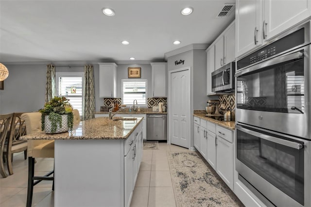 kitchen with white cabinets, stainless steel appliances, and a center island with sink