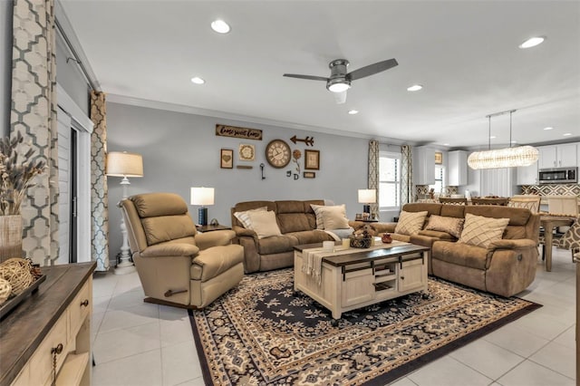 tiled living room featuring ceiling fan with notable chandelier and ornamental molding