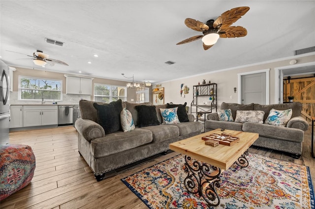 living room featuring a barn door, light hardwood / wood-style flooring, crown molding, a textured ceiling, and ceiling fan with notable chandelier