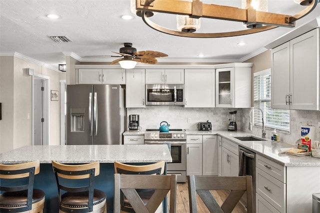 kitchen featuring ceiling fan, sink, decorative backsplash, white cabinets, and appliances with stainless steel finishes