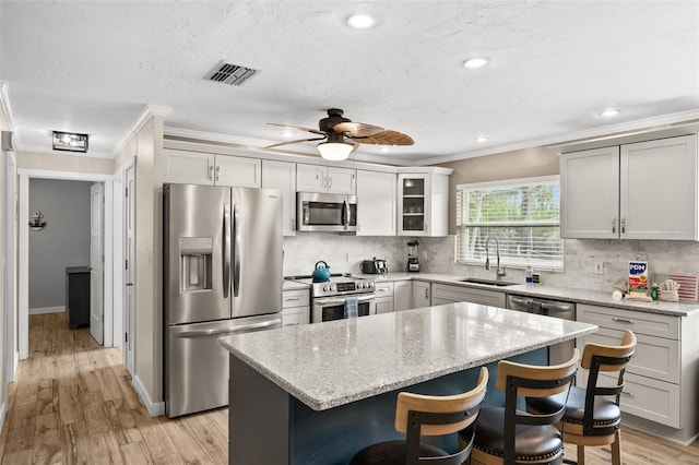 kitchen featuring light stone countertops, sink, a center island, stainless steel appliances, and backsplash