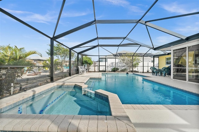 view of pool with glass enclosure, an in ground hot tub, and a patio