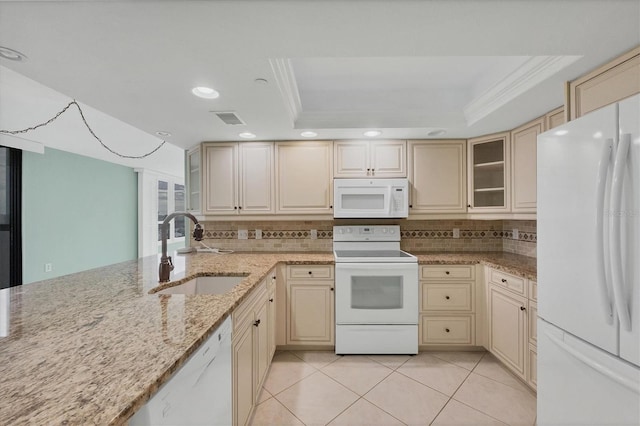 kitchen featuring light stone countertops, white appliances, a tray ceiling, and sink