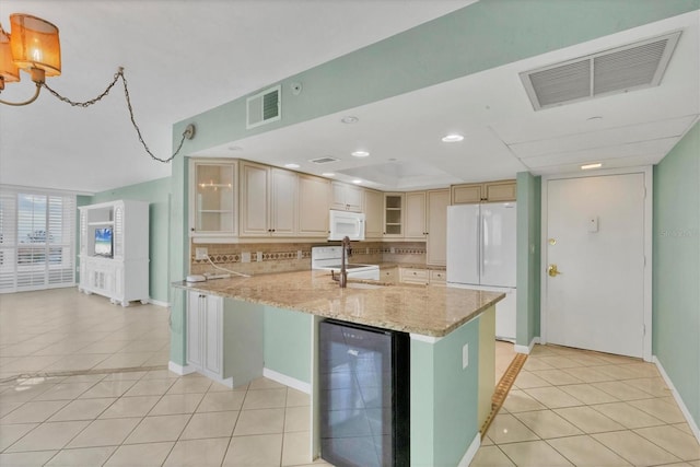 kitchen with light stone countertops, backsplash, white appliances, beverage cooler, and light tile patterned floors