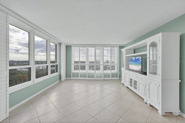 unfurnished living room featuring a water view and light tile patterned floors